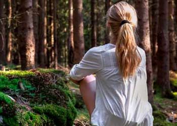 girl sitting peacefully in woods