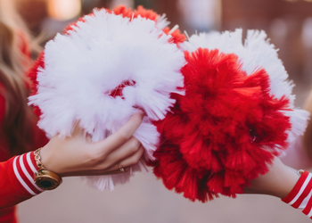 two cheerleaders holding pom poms together