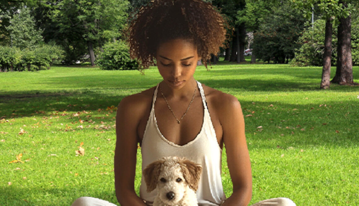 Woman sitting in yoga position with puppy sitting in front of her