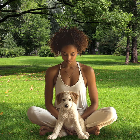 Woman sitting in yoga position with puppy sitting in front of her
