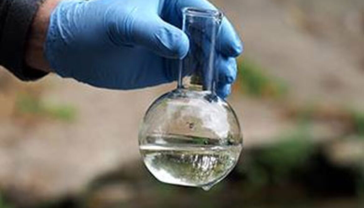 surgical glove holding flask with water over pond