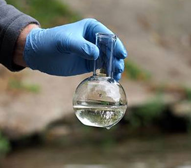 surgical glove holding flask with water over pond